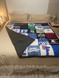 there is a bed with many t - shirts on it and a lamp next to it