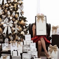 a woman sitting in front of a christmas tree holding up a sign that says instagram