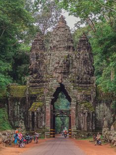 motorcycles are parked in front of the entrance to an ancient building with trees around it