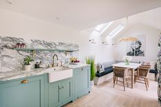 a kitchen with green cabinets and marble counter tops, along with a dining room table