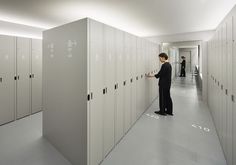 a woman standing in a hallway between two rows of lockers with writing on them