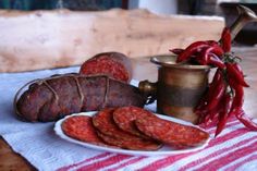 there is a plate with sausages on it next to a pot and pepperoni