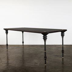 a wooden table sitting on top of a floor next to a white wall in an empty room