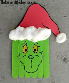 a green piece of paper with a santa hat on it's head and eyes