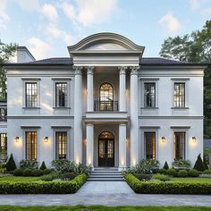 a large white house with many windows and bushes