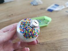 a person holding a small toy with sprinkles on it