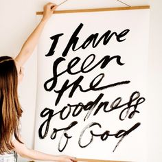 a woman standing in front of a white sign with writing on it that says, i have seen the goodness of god