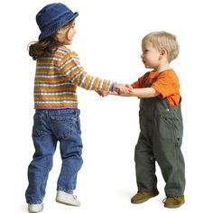 two young boys are holding hands and smiling at each other while standing in front of a white background