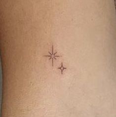 a small star tattoo on the side of a woman's stomach, with two smaller stars above it