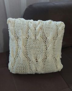 a white knitted pillow sitting on top of a couch