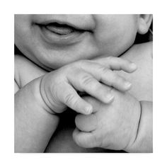 a black and white photo of a baby holding it's hand up to the camera