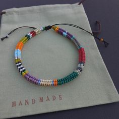 a multicolored beaded bracelet with tassels sits on a drawstring bag