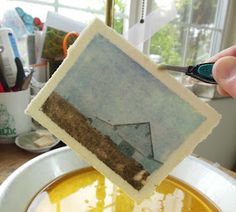 a person holding a piece of paper over a yellow liquid