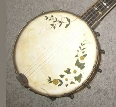 a close up of an old style musical instrument on the ground with flowers painted on it