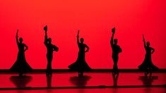 the silhouettes of dancers in front of a red sky