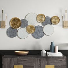 the wall is decorated with gold, silver and white plates hanging on it's sideboard