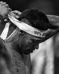 black and white photograph of a shirtless man tying his headband