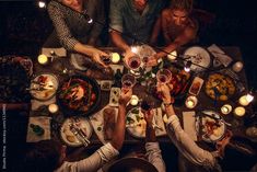 a group of people sitting around a table with food and wine glasses on top of it