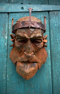 a wooden mask hanging on the side of a green door