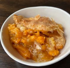 a white bowl filled with food on top of a wooden table