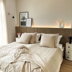 a bed with white sheets and pillows in a bedroom next to a wall mounted pictures