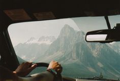 a person driving a car with mountains in the background