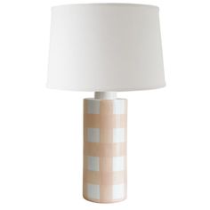 a table lamp with a white shade on the top and a light brown base in front of it