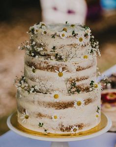 a white wedding cake with daisies on top