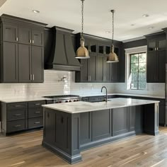 a large kitchen with gray cabinets and white counter tops, an island in the middle