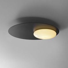 a round light fixture on the ceiling in a room with grey walls and flooring