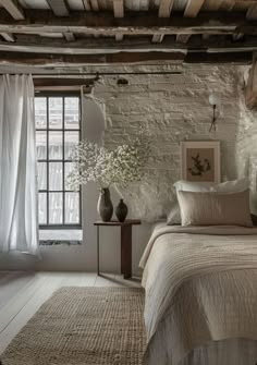 a bedroom with exposed brick walls and white bedding in the corner, along with two vases on either side of the bed