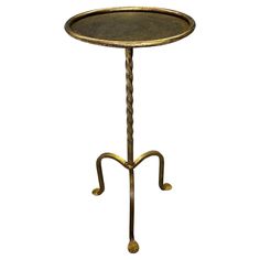 a metal table with two legs and a round tray on the top that is holding a candle holder