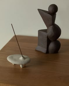 a small white object sitting on top of a wooden table next to a black sculpture