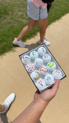 a person holding up a box of golf balls