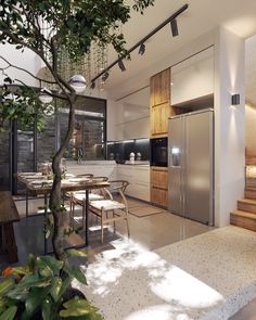 an open kitchen and dining area with stairs leading up to the upper floor, next to a tree