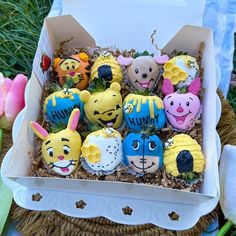 a box filled with lots of different types of decorated cupcakes on top of grass