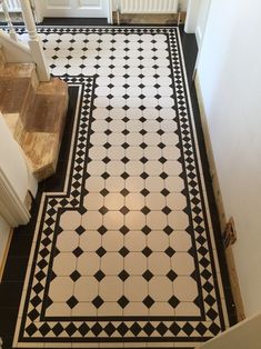 a black and white tiled floor in a house with stairs leading up to the door