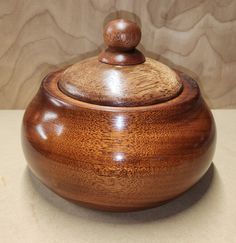 a wooden bowl with a lid on a table