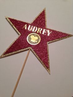 a red and gold star shaped cake topper with the name audrey on it