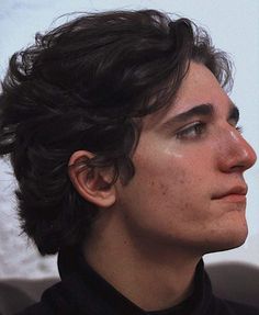 a close up of a person with freckles on his hair and wearing a black shirt