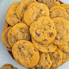 chocolate chip cookies piled on top of each other in a wooden bowl next to another cookie