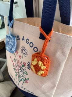 an orange crocheted bag hanging from a blue strap with a flower design on it