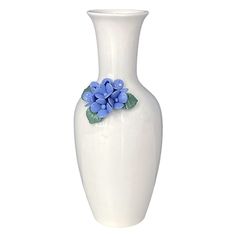 a white vase with blue flowers on the top and green leaves in the bottom, against a white background