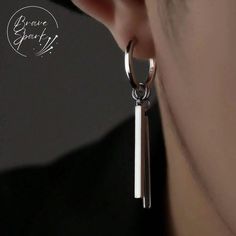 a close up of a person's ear wearing silver earrings with long bars hanging from them