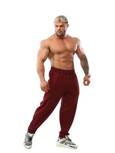 a shirtless man in red sweatpants posing for the camera with his hands on his hips