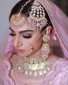 a woman in a pink outfit with gold jewelry on her head and veil over her face