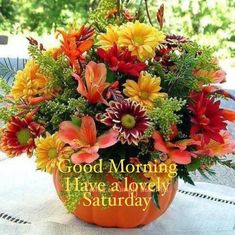 a vase filled with lots of flowers sitting on top of a white table covered in leaves