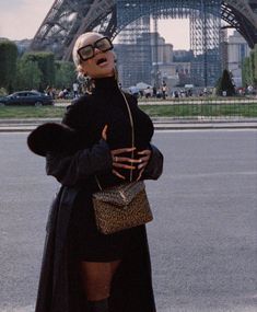 a woman standing in front of the eiffel tower with her hand on her hip