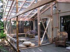 a wooden deck with chairs and a caged in area on the side of a house