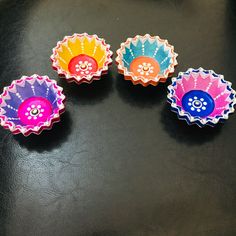 four colorful paper plates sitting on top of a black table next to an orange, pink, blue and yellow cupcake